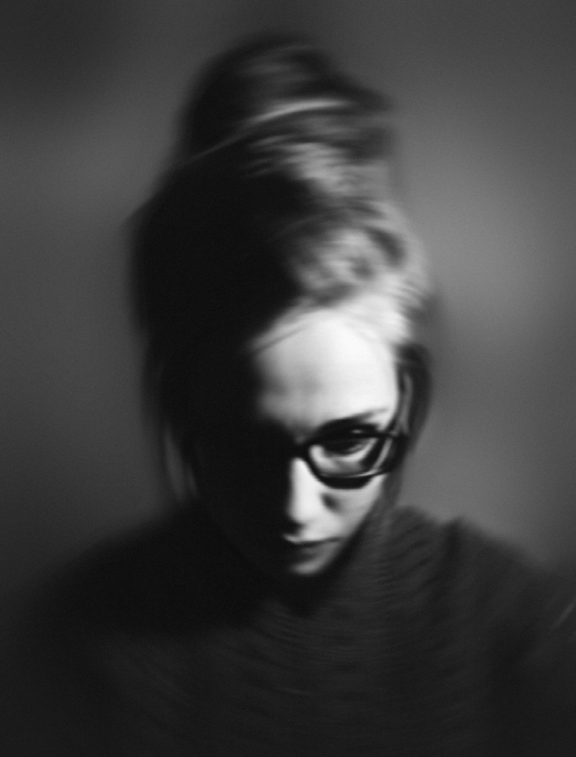 pexels-photo-3570362-3570362 Grayscale portrait of a woman with glasses, exhibiting a pensive mood in studio lighting.